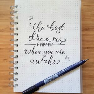 the best dreams happen when you are awake notebook and black pen